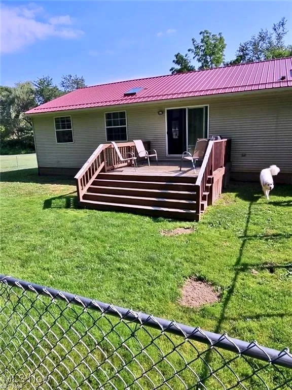 Rear view of property with a deck and a lawn
