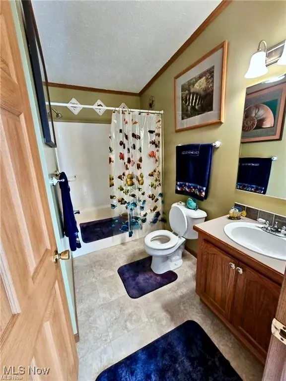 Full bathroom with a shower stall, vanity, a textured ceiling, ornamental molding, and light tile patterned flooring