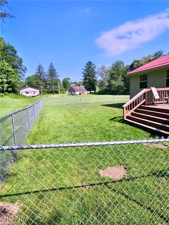 Fenced backyard featuring a deck and view of wooded area