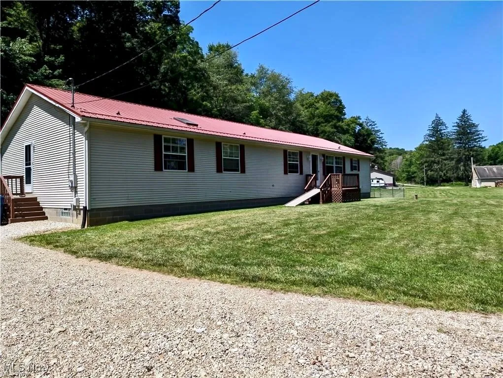View of front of home featuring a metal roof, a front lawn, and a deck