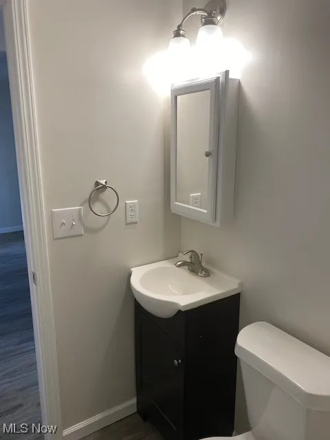 Half bathroom with vanity and dark wood-style flooring