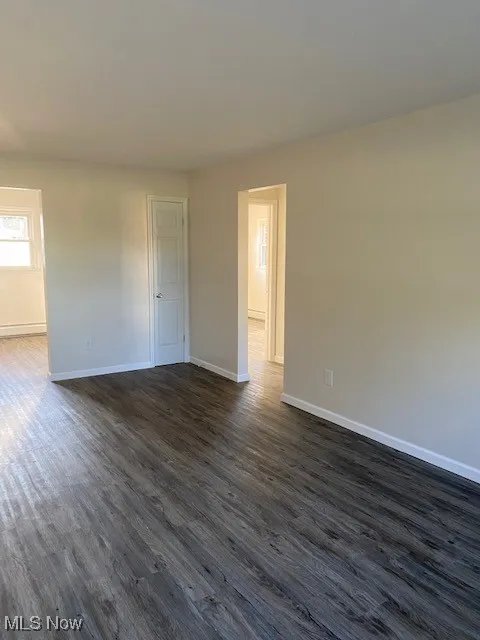 Spare room featuring dark wood-style floors and baseboards