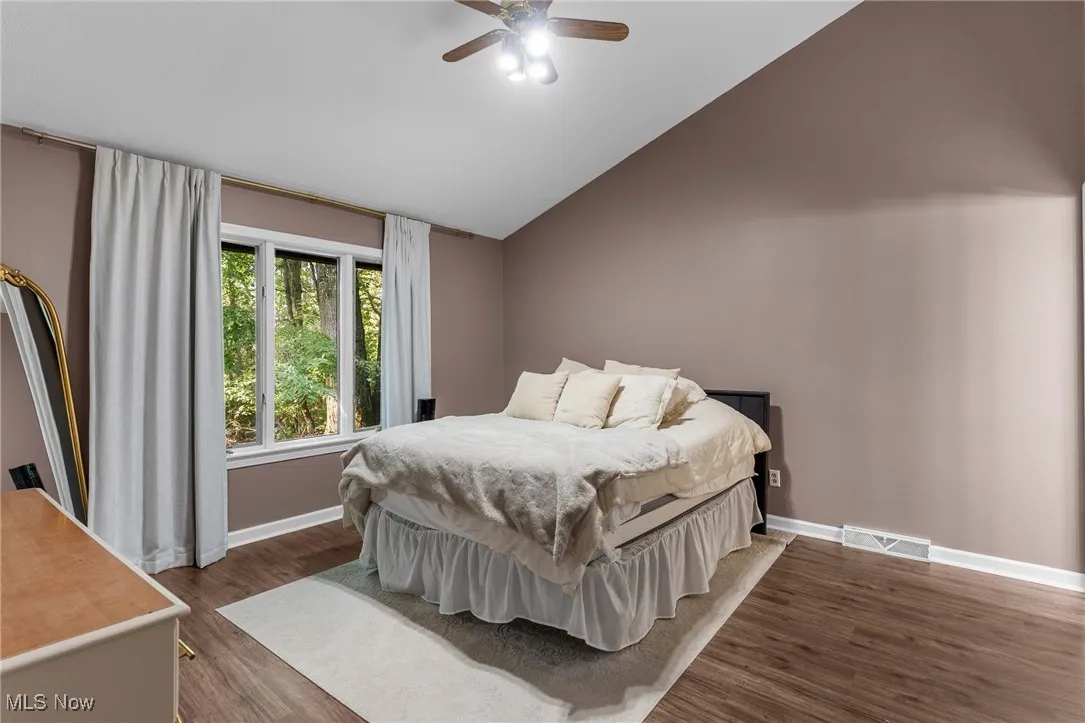 Bedroom with dark wood-style flooring, lofted ceiling, and ceiling fan