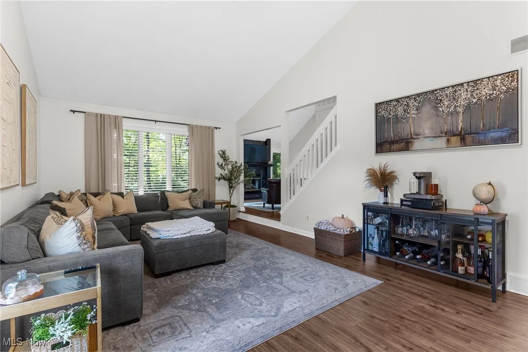 Living area with high vaulted ceiling, wood finished floors, and stairway