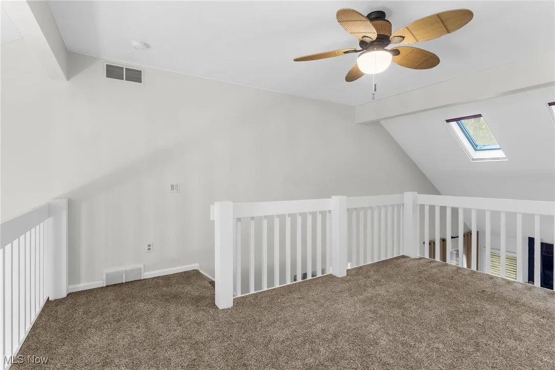 Additional living space featuring ceiling fan, a skylight, and carpet floors
