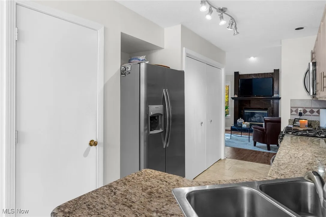 Kitchen with appliances with stainless steel finishes, light wood-type flooring, light stone counters, and a fireplace
