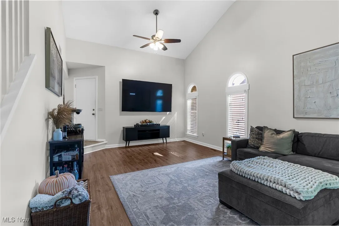 Living room with high vaulted ceiling, ceiling fan, and wood finished floors