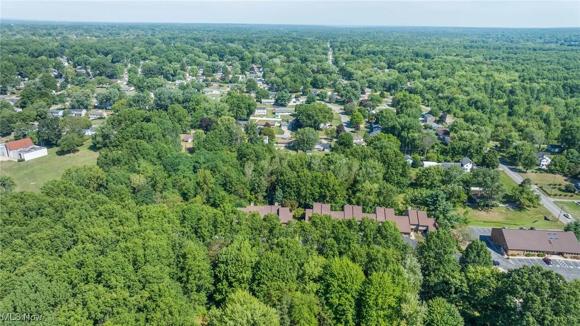 Aerial view of property and surrounding area featuring a forest
