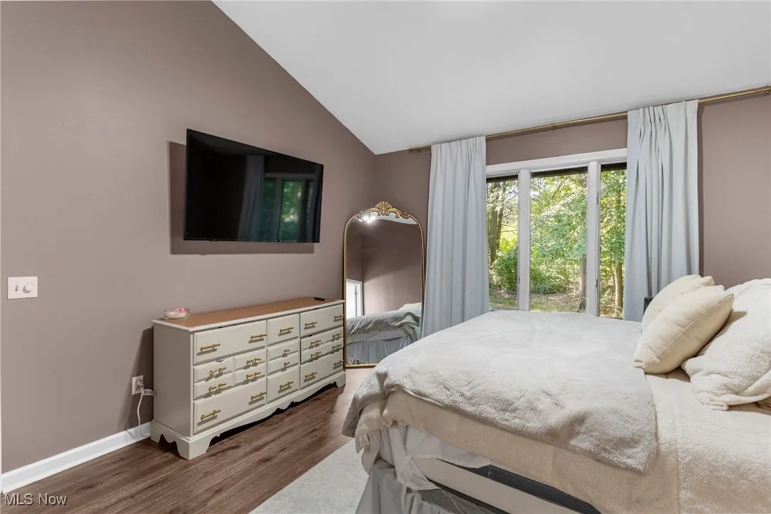 Bedroom with dark wood-type flooring and vaulted ceiling