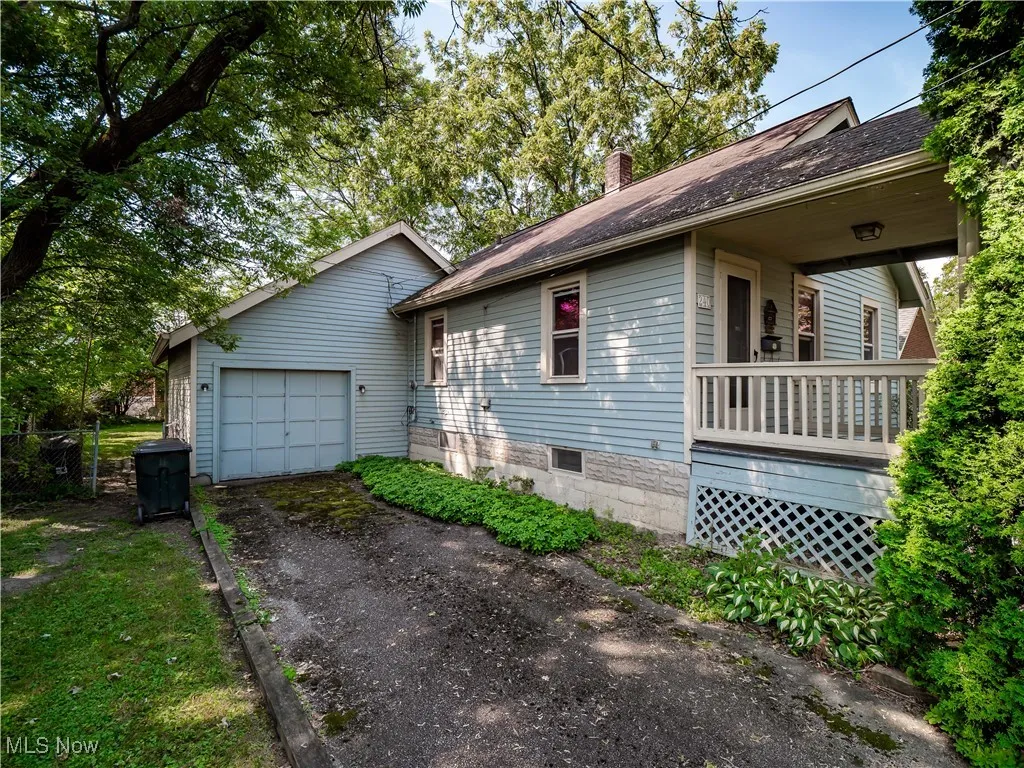 View of side of home with asphalt driveway, a chimney, an attached garage, and a shingled roof