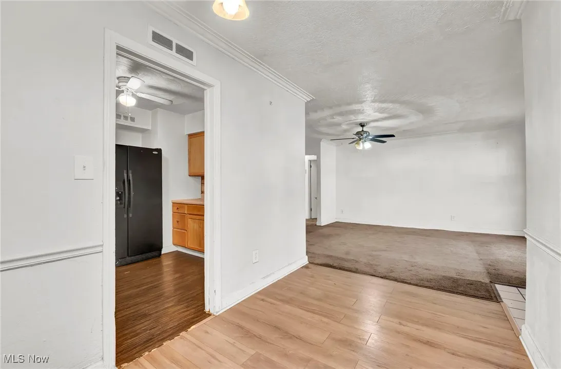 Unfurnished room featuring a ceiling fan, crown molding, a textured ceiling, and light wood-style floors