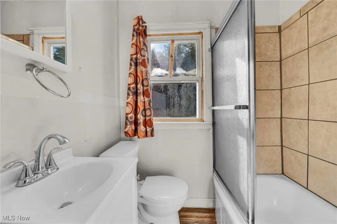 Bathroom featuring bath / shower combo with glass door, vanity, and wood finished floors