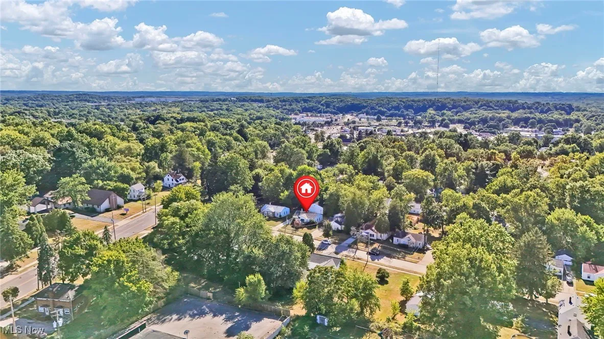 Aerial view of property and surrounding area with a forest and nearby suburban area