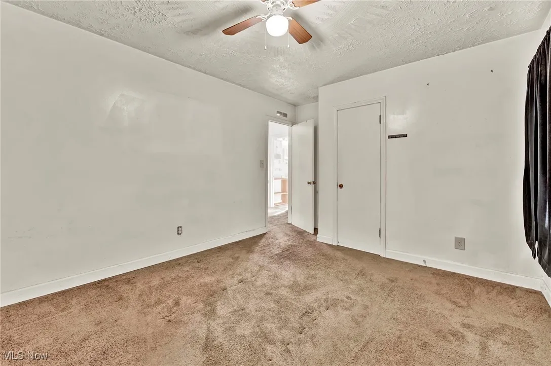 Unfurnished bedroom with a textured ceiling, carpet, and a ceiling fan