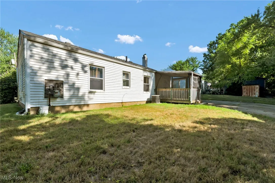 Rear view of property featuring a sunroom and a yard