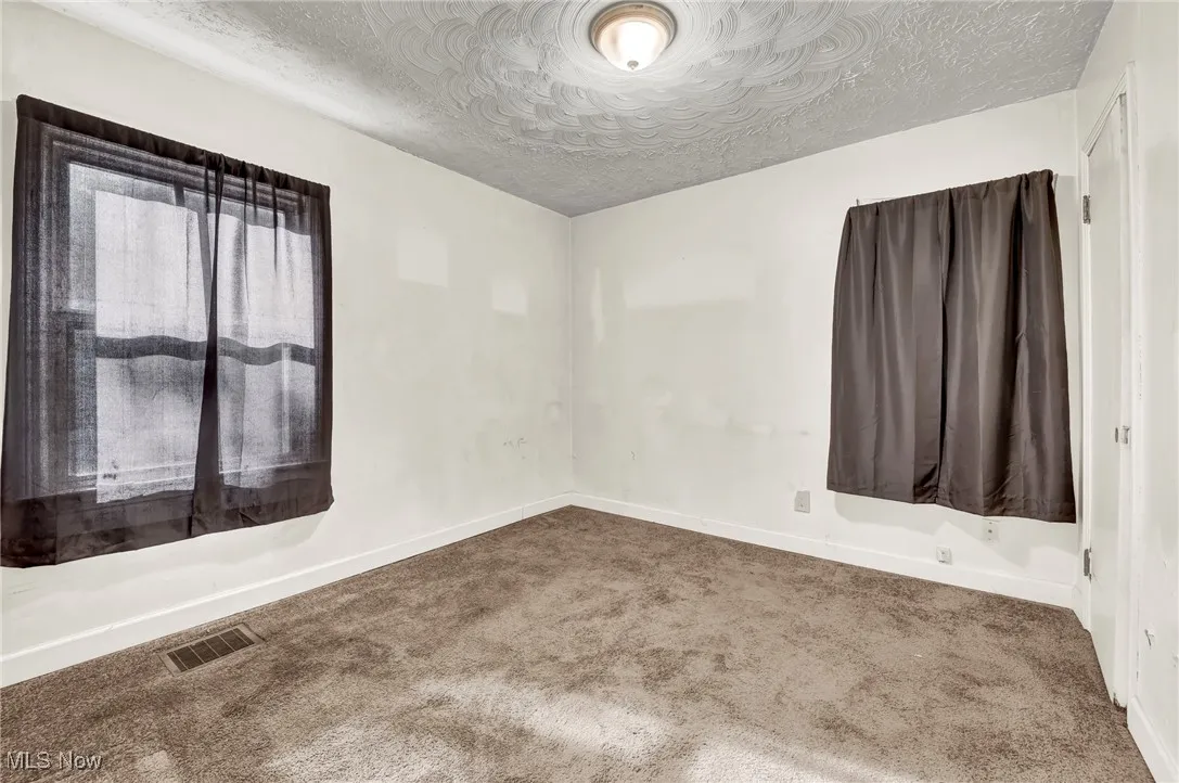 Empty room with a textured ceiling and carpet