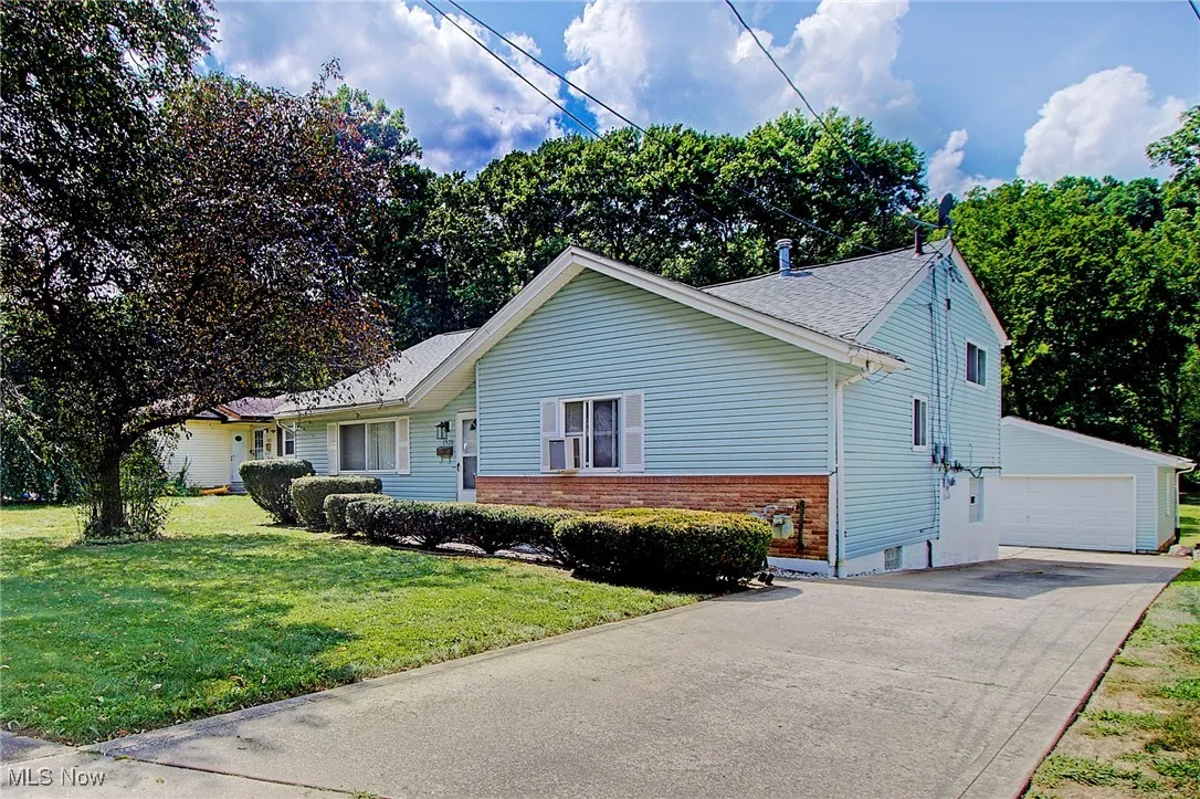 View of front of house featuring brick siding, a garage, a front yard, and roof with shingles