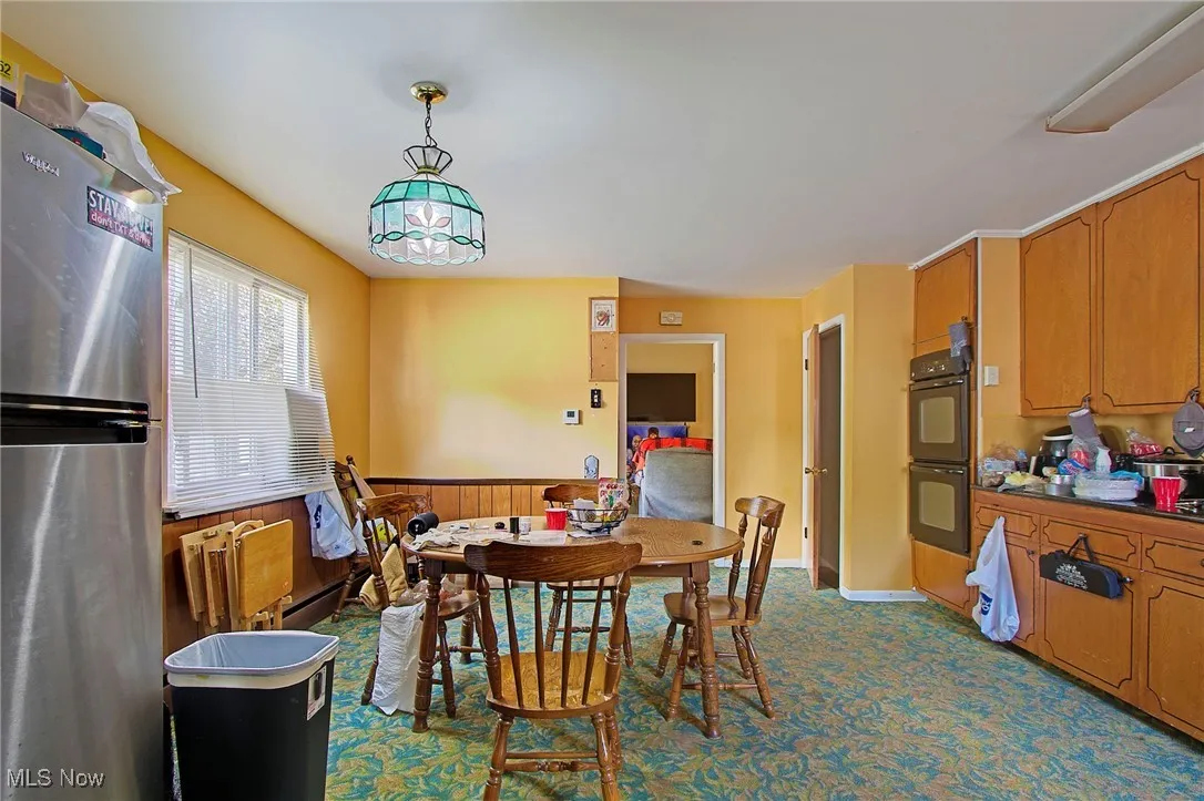 Dining area featuring wooden walls, wainscoting, and dark carpet