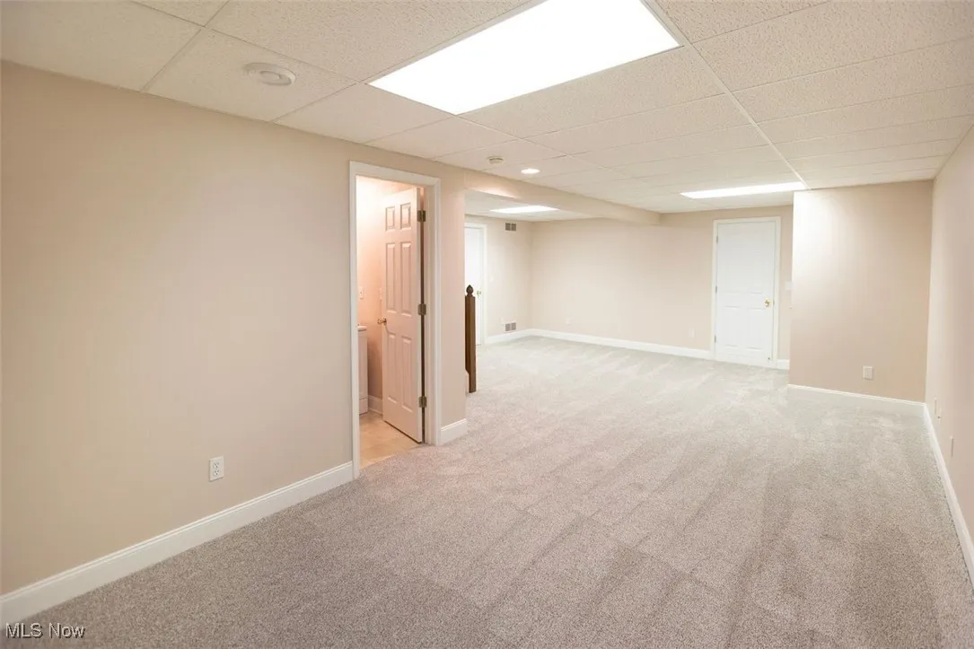 Finished rec room with light colored carpet and a paneled ceiling