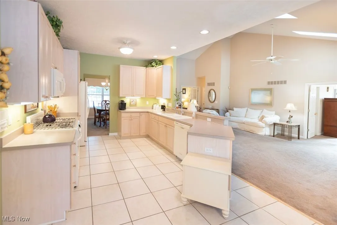 Kitchen featuring open floor plan, a peninsula, light countertops, light carpet, and light tile patterned flooring