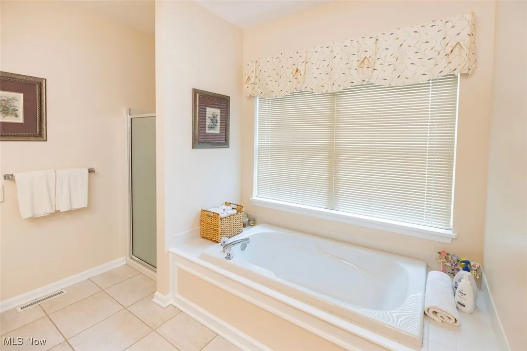 Master Bathroom featuring a soaking tub, a shower stall, and light tile patterned floors