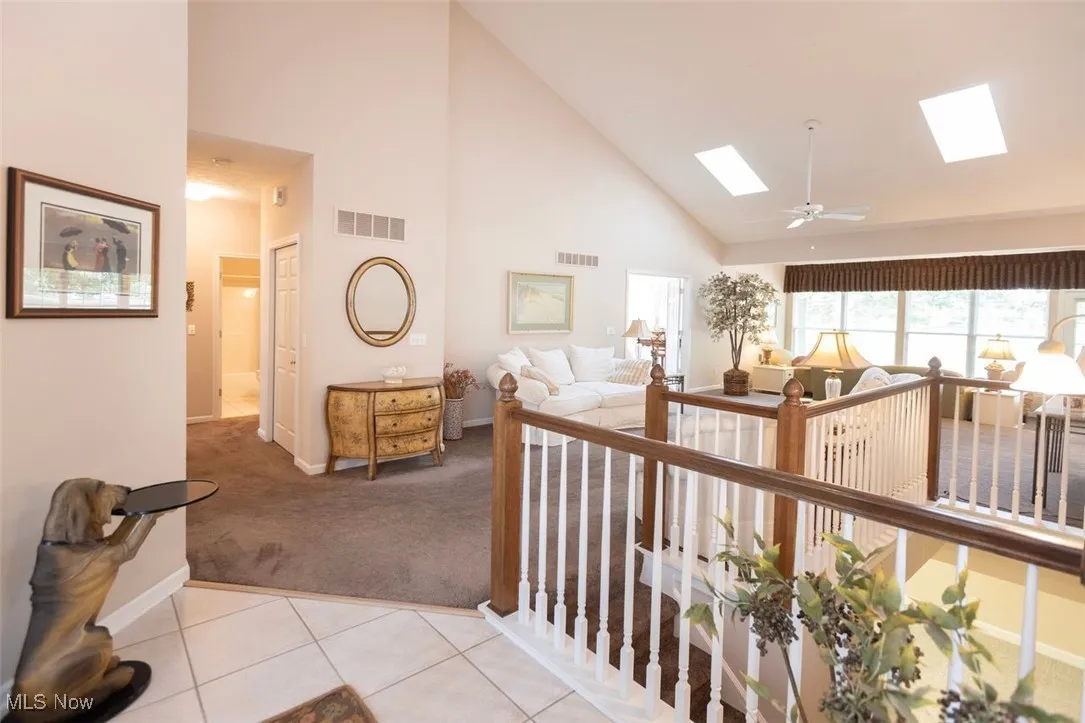 Front entry foyer featuring high vaulted ceiling, light carpet, light tile floors, and a view into the great room with skylights