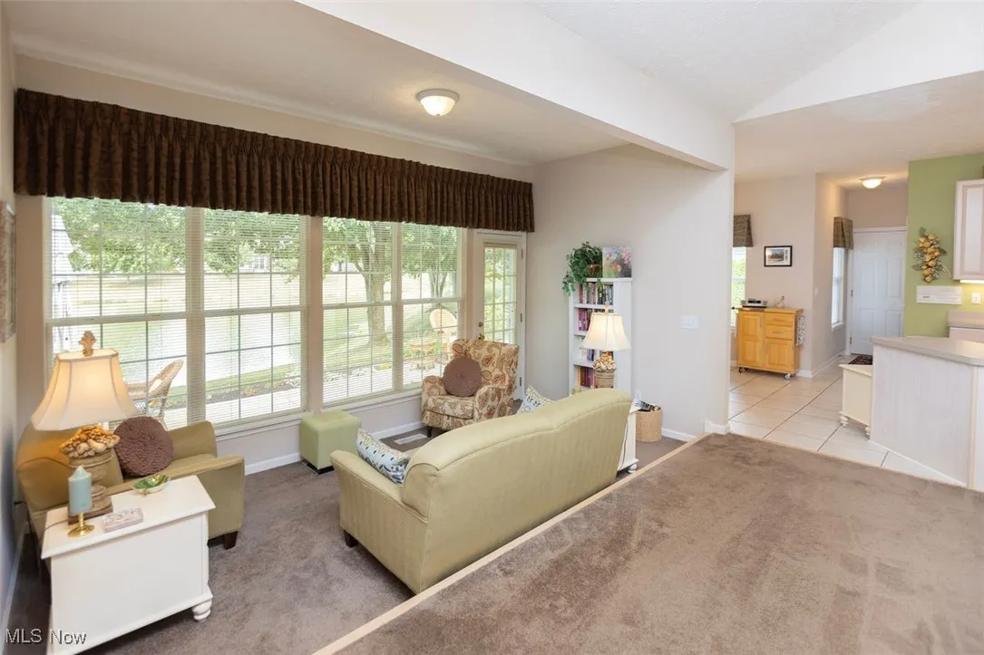 Sun Room featuring dark carpet, vaulted ceiling, with a view of the morning rm and kitchen
