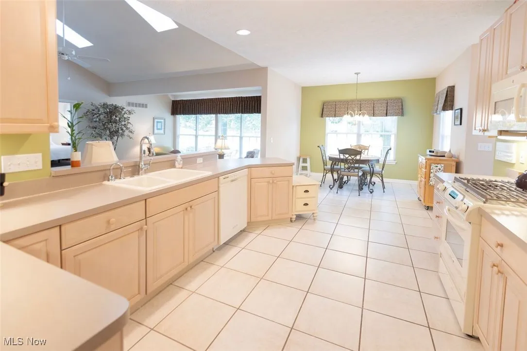 Kitchen featuring white appliances, light tile patterned flooring, recessed lighting, light countertops, and light cabinetry