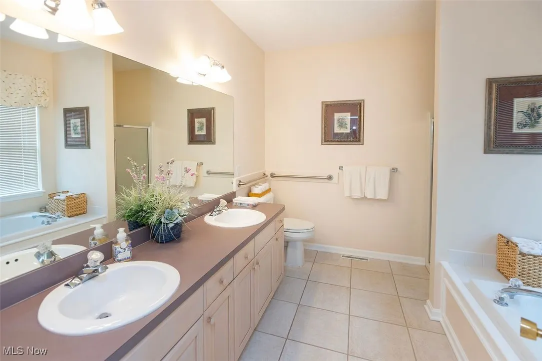 Master Bathroom with light tile patterned floors, a stall shower, a bath, and double vanity