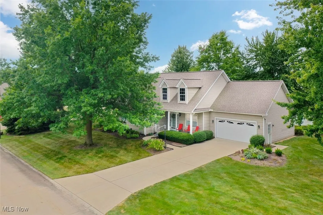 View of front facade featuring a porch, an attached garage, a front lawn, and concrete driveway