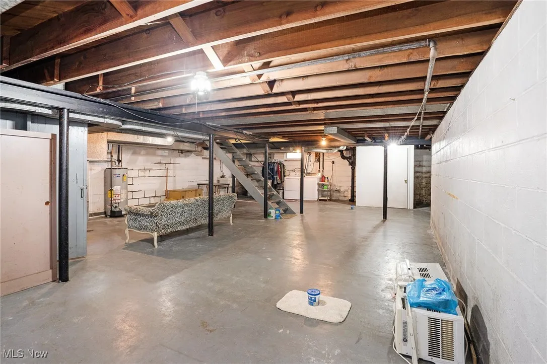 Unfinished basement featuring stairway, washer / dryer, and water heater