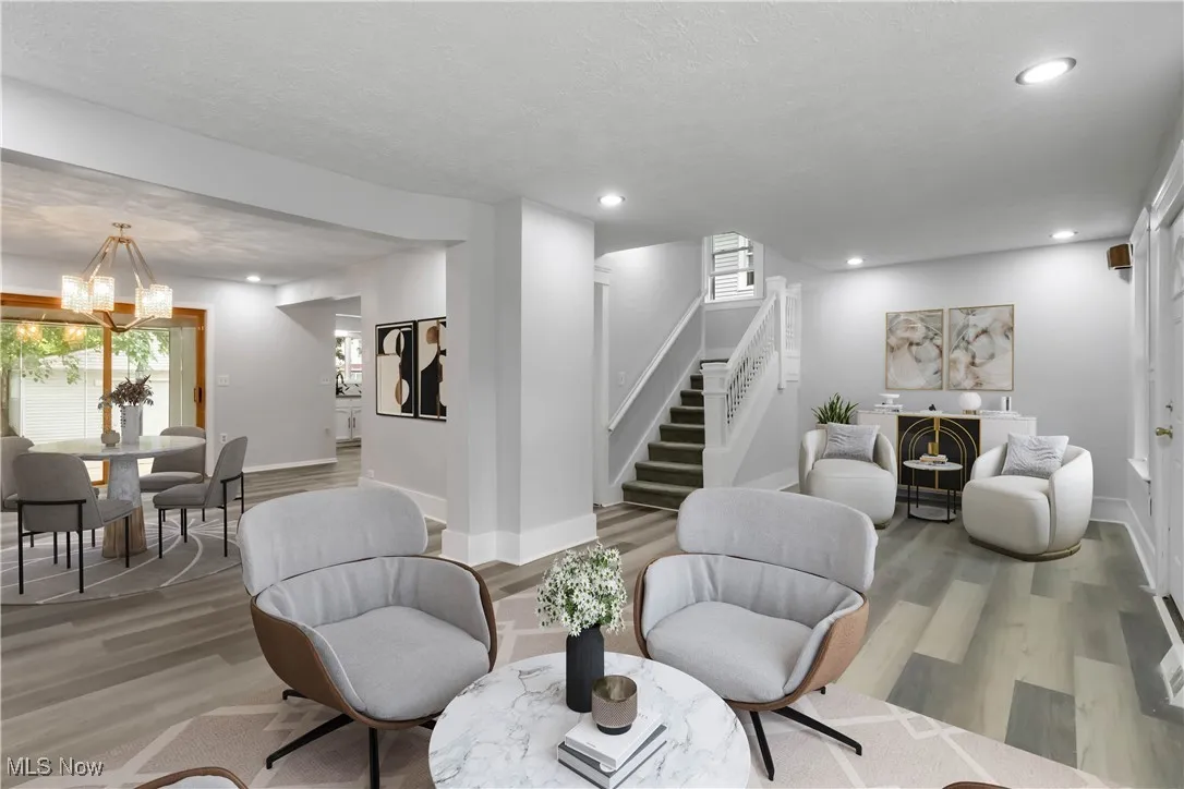 Sitting room with wood finished floors, stairs, healthy amount of natural light, recessed lighting, and a textured ceiling