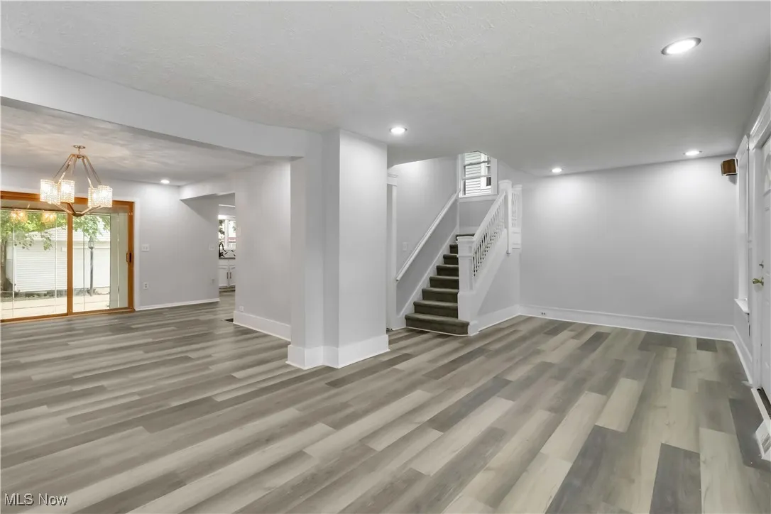 Basement with light wood-type flooring, stairs, recessed lighting, a textured ceiling, and a chandelier