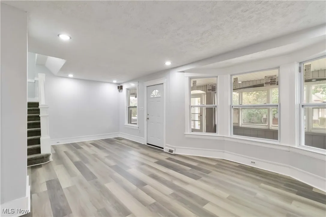 Foyer featuring healthy amount of natural light, light wood-type flooring, recessed lighting, a textured ceiling, and stairway
