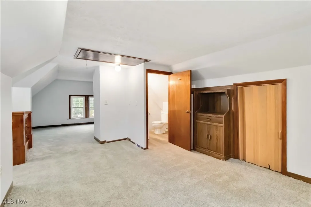 Bonus room featuring attic access, light colored carpet, and lofted ceiling