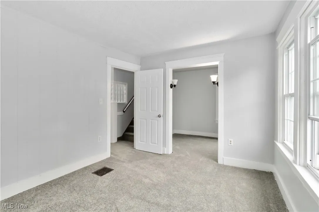 Unfurnished bedroom with light carpet and baseboards