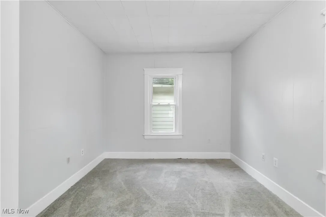 Empty room featuring light colored carpet and baseboards