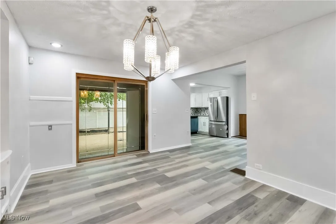 Unfurnished dining area featuring light wood-style flooring and a chandelier