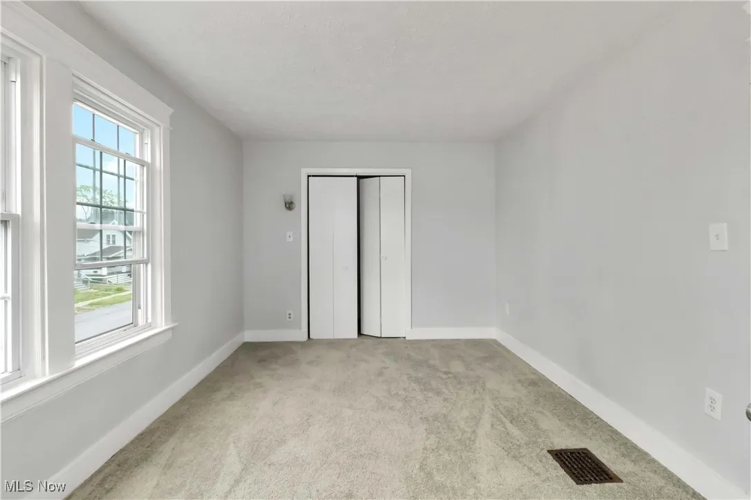 Unfurnished bedroom featuring light carpet and a closet