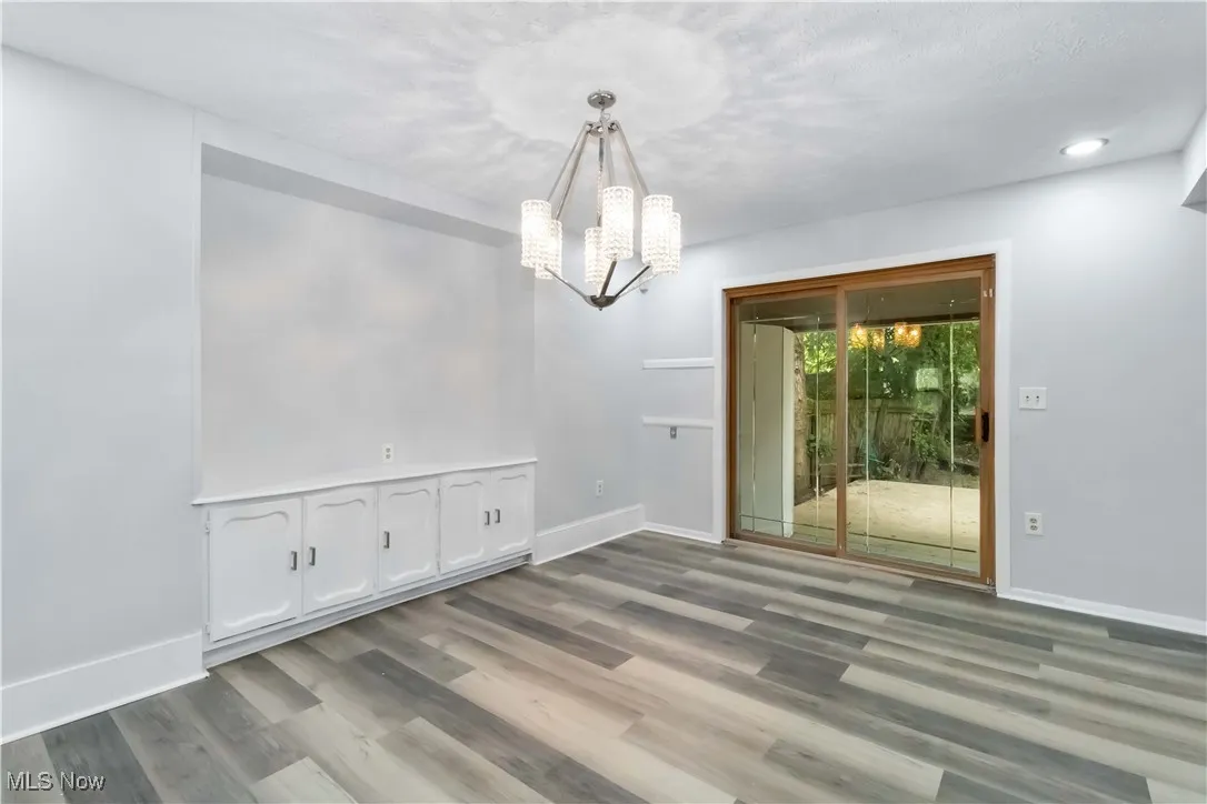 Unfurnished dining area featuring wood finished floors and a chandelier