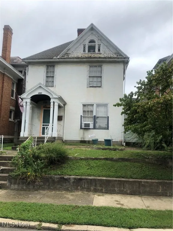 Victorian house with a chimney and a front lawn