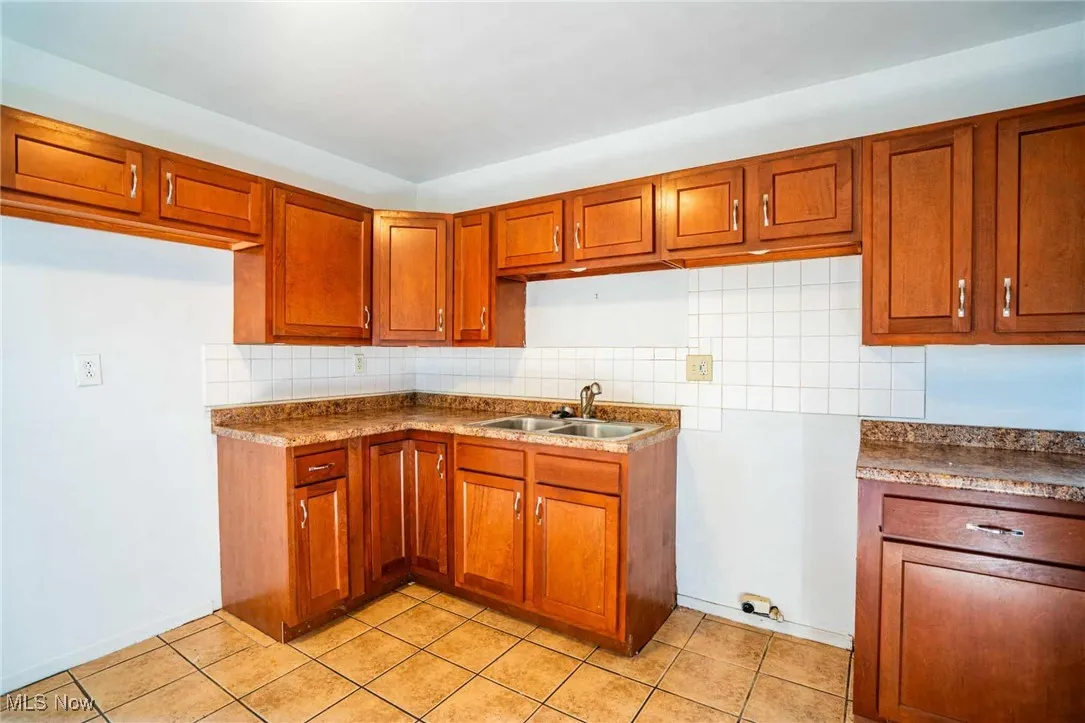 Kitchen with brown cabinetry, tasteful backsplash, and light tile patterned flooring