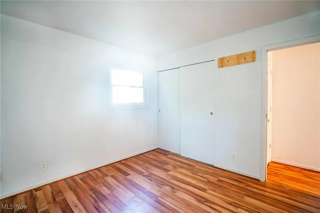 Unfurnished bedroom with wood finished floors and a closet