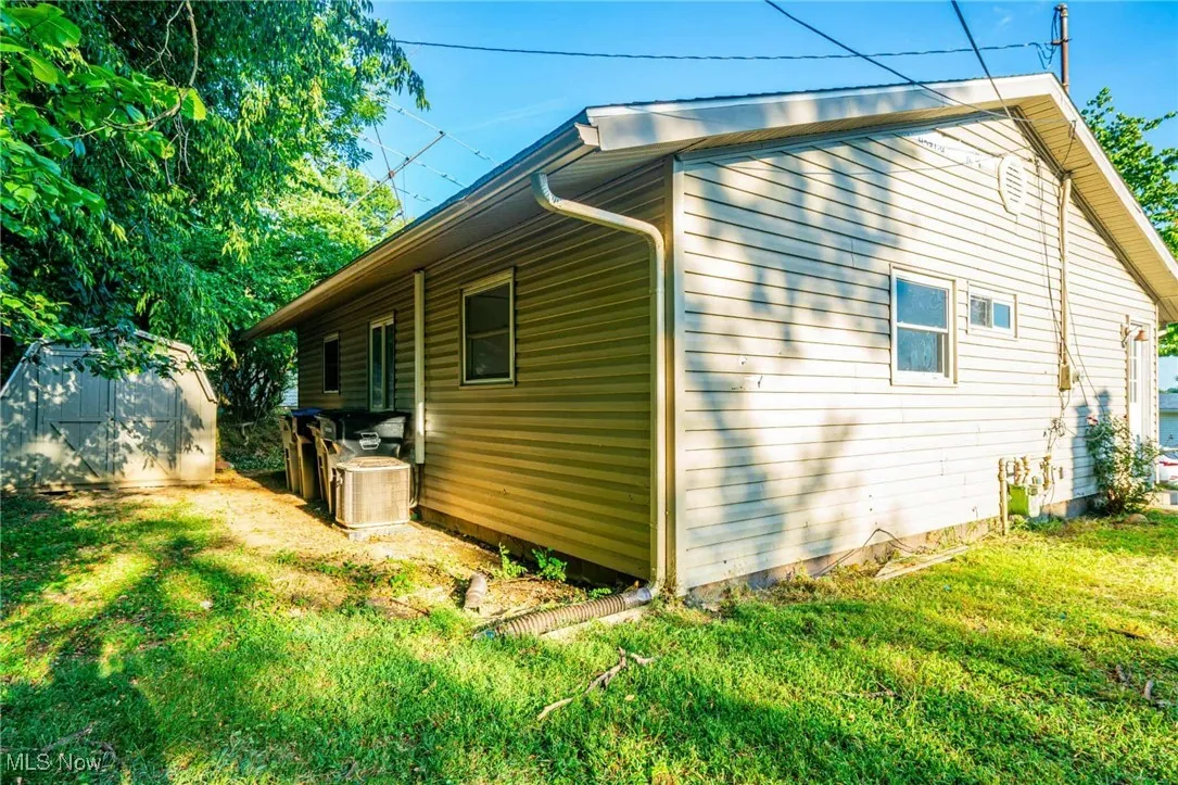 View of property exterior with a lawn and a storage unit