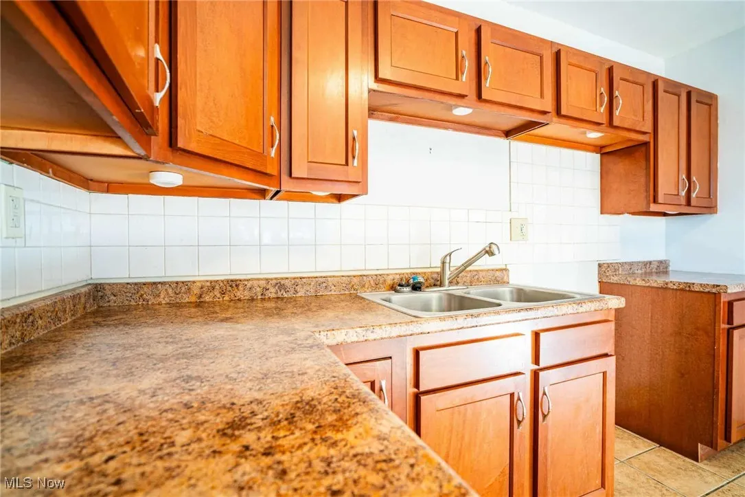 Kitchen featuring decorative backsplash, brown cabinetry, light countertops, and light tile patterned floors