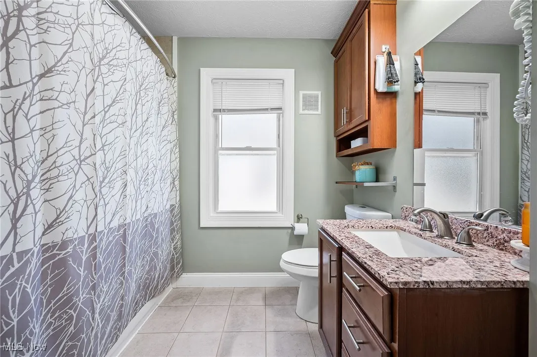 Bathroom featuring vanity, light tile patterned floors, a textured ceiling, and a shower with shower curtain