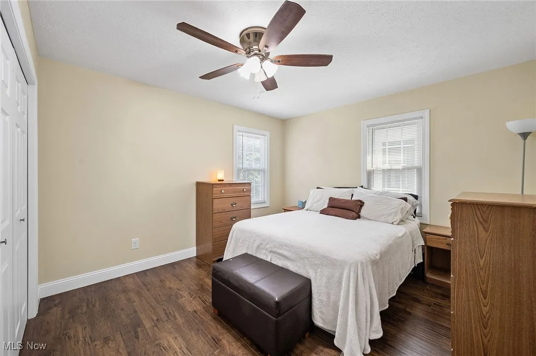 Bedroom 1 with dark wood-style flooring, a textured ceiling, ceiling fan, and a closet