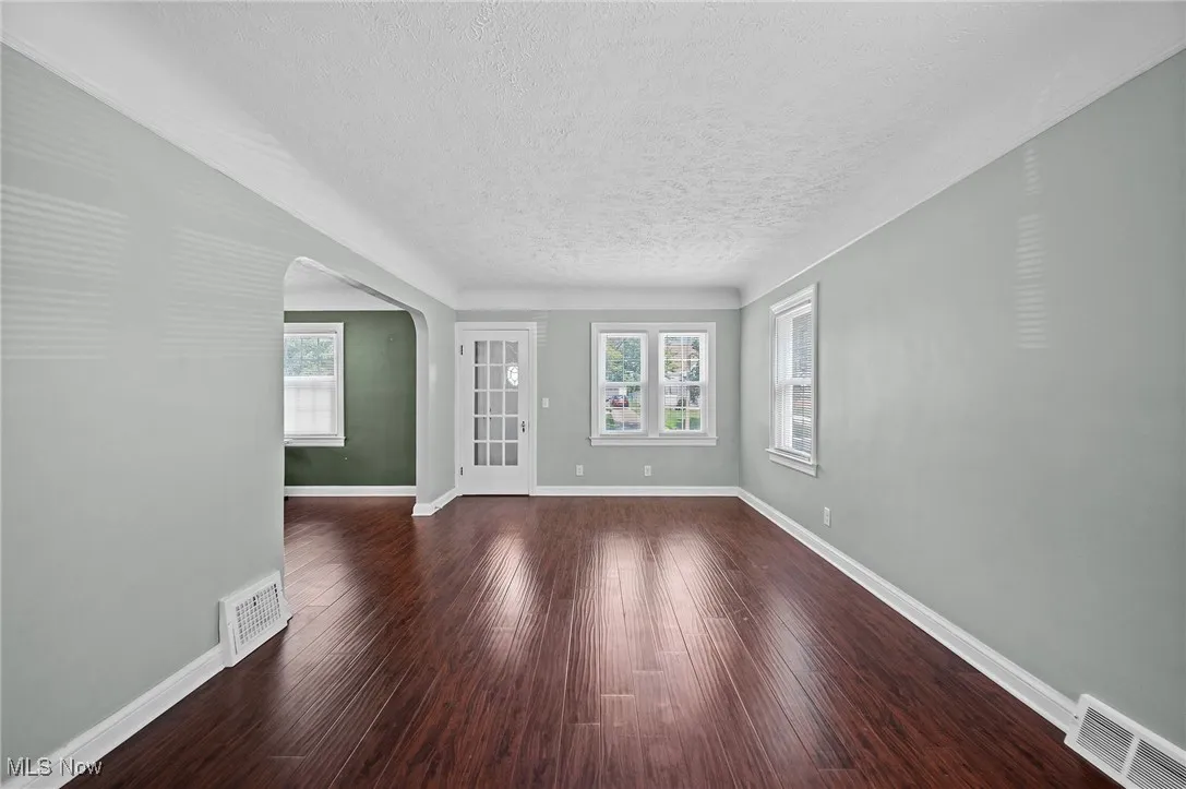 Living room featuring arched walkways, dark wood-style flooring, and a textured ceiling
