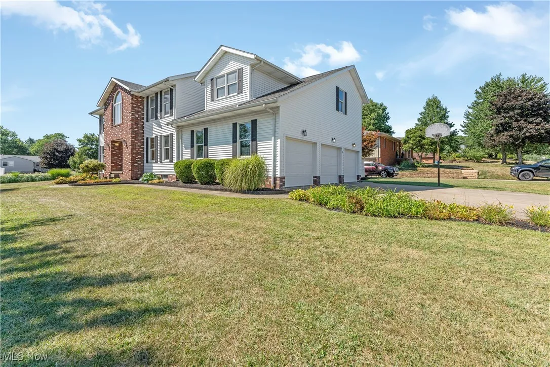 View of front and side of home with a garage, driveway, and a front lawn