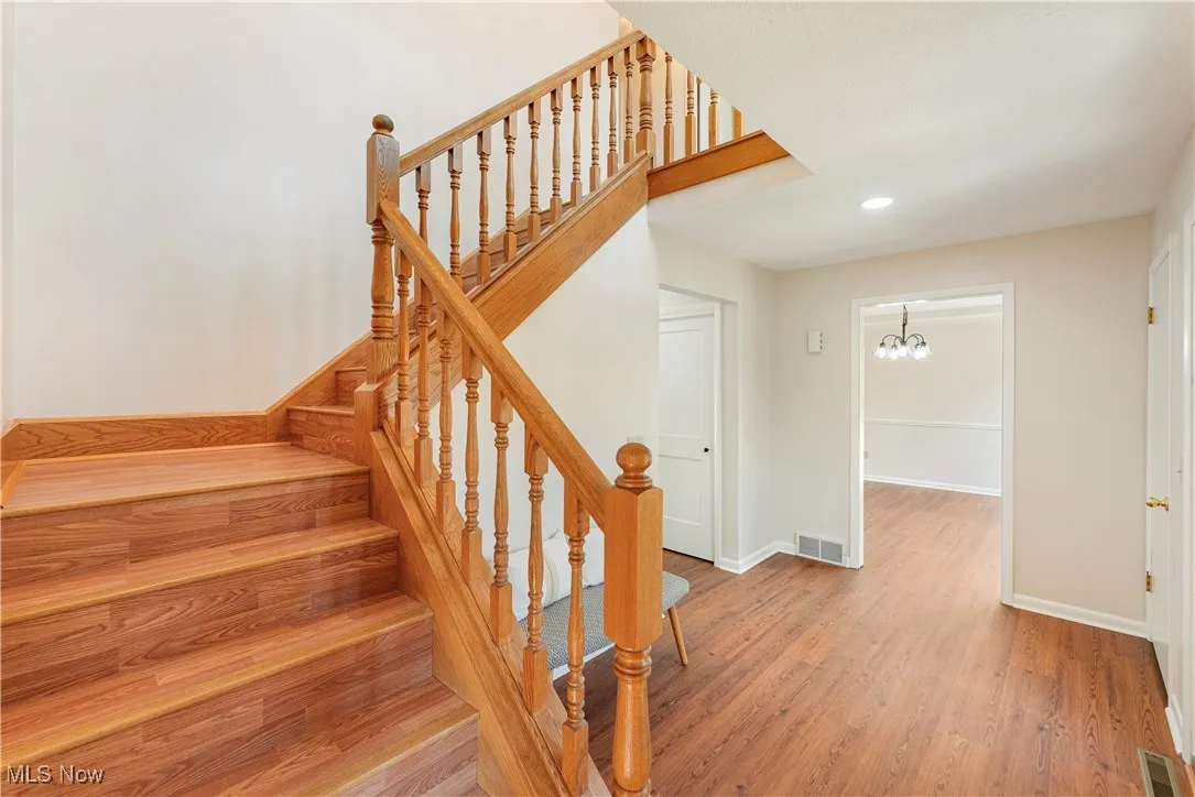 Stairs with wood finished floors, recessed lighting, and a chandelier